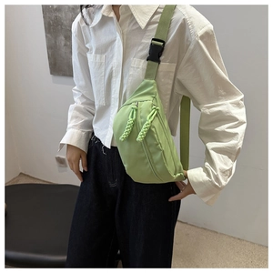 Detail of mint green nylon chest bag featuring braided zipper pulls and plastic buckle