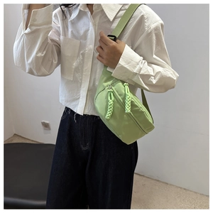 Close-up of light green nylon waist bag featuring dual woven rope zipper pullers