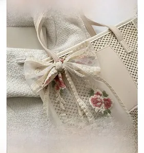 Detailed close-up of straw tote bag featuring lace bow with floral embroidery