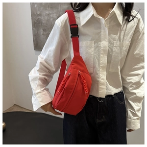 Detail of red nylon crossbody chest bag showing buckle and textured fabric strap
