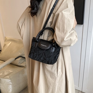Chic black quilted bucket bag with top handle and shoulder strap for 2024 fashion