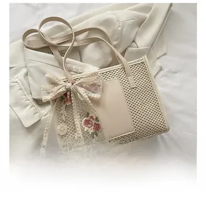 Close-up of woven straw tote bag with lace floral bow and leather patch on white blazer