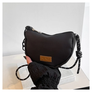 Dettaglio borsa hobo nera con tracolla in corda ed etichetta in pelle su bianco