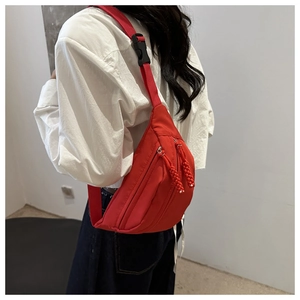 Detail of red nylon crossbody bag with matching zipper and black plastic buckle on strap