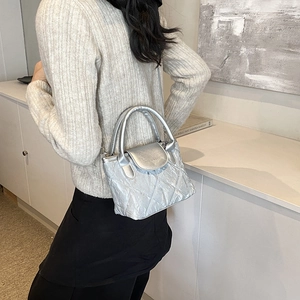 Silver quilted bucket bag with crossbody strap and top handle for elegant summer style