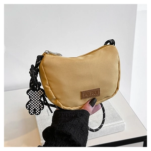 Dettaglio della borsa a mezzaluna in nylon giallo senape con tracolla intrecciata