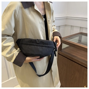 Minimalist black nylon crossbody chest bag worn with a khaki trench coat for daily use