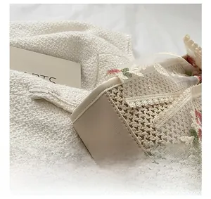Close-up of woven straw tote bag with delicate white lace trim and floral embroidery