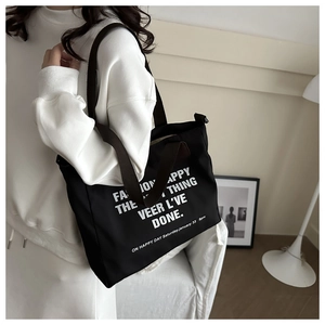 Détail d'un sac fourre-tout en toile noire avec lettrage mode et bretelles robustes