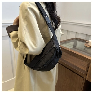 Detail of adjustable strap and plastic buckle on a black nylon crossbody fanny pack