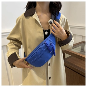 Detail of blue nylon crescent bag featuring adjustable strap and buckle on a model