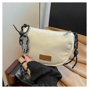 Dettaglio borsa a tracolla beige con logo in pelle e ciondolo orsetto a scacchi