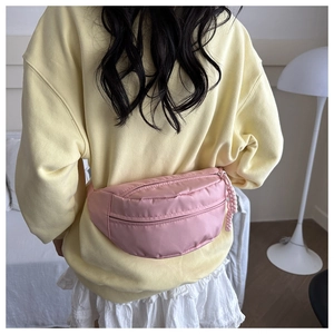 Detail of pink nylon waist bag with rope zipper pull worn by a model in casual wear