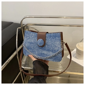 Détail du sac bandoulière en tweed bleu avec rabat en cuir brun et chaîne argentée