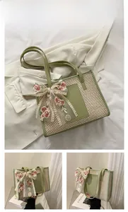Detail of green straw tote bag featuring elegant lace floral bow and leather handles