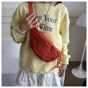 Detail of orange crescent crossbody bag with braided cord zipper puller for casual wear