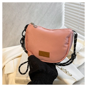Dettaglio borsa a mezzaluna rosa con tracolla intrecciata e patch logo in pelle