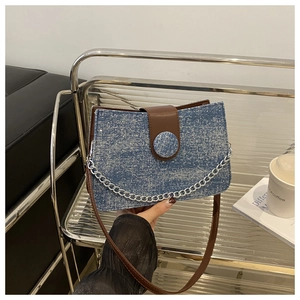 Détail du tissu à paillettes bleues et du rabat en cuir marron d'un sac à bandoulière chic