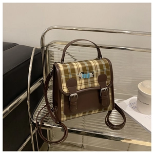 Detail of vintage plaid messenger bag with dachshund embroidery on a metal shelf