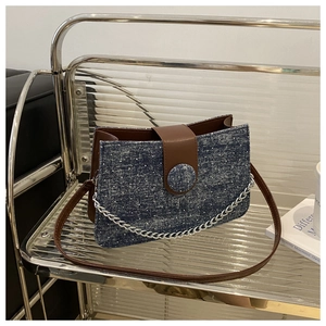 Détail du sac sous le bras en denim vintage avec chaîne argentée et bandoulière en cuir