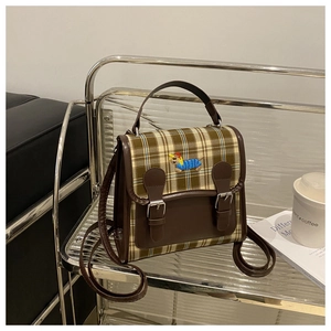 Close-up of vintage plaid backpack with cartoon dog embroidery and leather strap detail