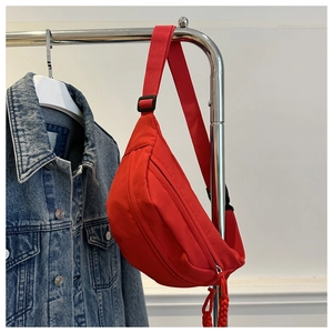 Close-up of bright red nylon waist bag with adjustable strap hanging on a metal rack