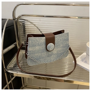 Détail du sac sous le bras en denim vintage avec paillettes et rabat en cuir brun