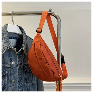 Detail of an orange crescent nylon chest bag featuring an adjustable strap and buckle