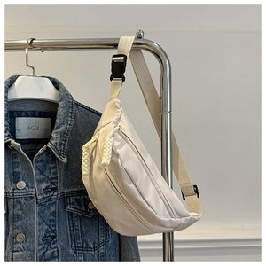 Detail of off-white nylon crescent bag with woven zipper pull and adjustable strap