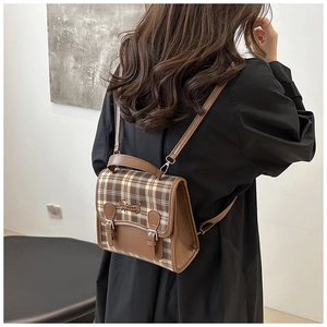 Detail of a brown plaid mini backpack with leather trim and cute dachshund embroidery