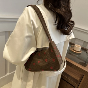 Sac à bandoulière en velours côtelé marron avec broderie fraise en style lifestyle
