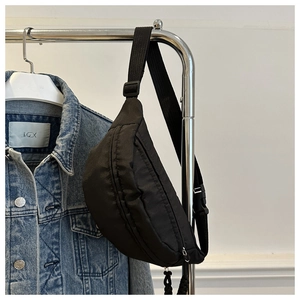 Close-up of black nylon crescent fanny pack hanging on a metal display rack