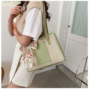 Detail of green straw tote bag with floral lace bow and leather handle for summer