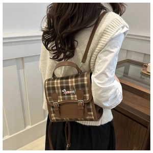Detail of a brown plaid backpack featuring a cute dachshund embroidery and metal buckles