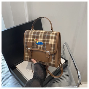 Detail of checkered shoulder bag with dachshund embroidery and metal buckle closure