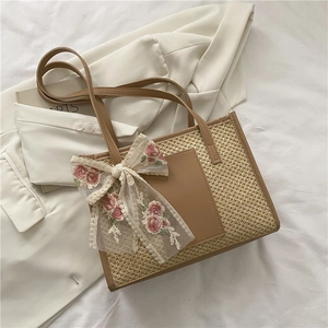 Detail of straw tote bag featuring a floral lace bow and woven texture on a blazer background