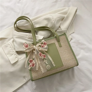 Detailed view of straw tote bag featuring floral embroidery and mesh bow decoration