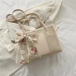Detail of cream woven tote bag featuring delicate lace bow and floral embroidery decoration