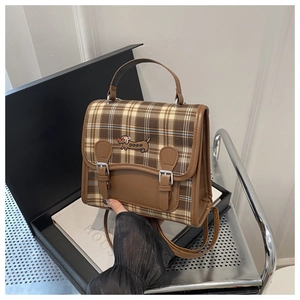 Detail of British style plaid backpack with dachshund embroidery and leather buckles