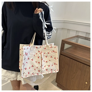 Détail du sac cabas en toile à imprimé cerise rouge, poches avant et bandoulière
