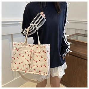 Détail du sac fourre-tout en toile beige imprimé cerises avec double poche et bandoulière