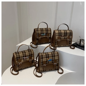 Detail of four retro brown plaid backpacks with cartoon dog embroidery on white stand