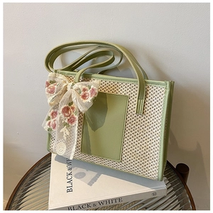 Detail of woven straw tote bag featuring white lace bow with pink floral embroidery