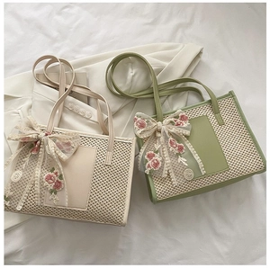 Detail of cream and green woven tote bags with lace floral ribbons and leather pockets