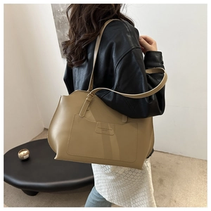 Détail d'un grand sac cabas en cuir beige avec poche avant et bretelles réglables