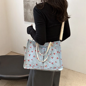 Sac cabas en toile bleue à motif cerises et doubles poches porté par un mannequin