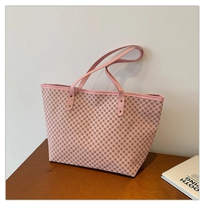 Detail of pink tote bag with geometric pattern and slim shoulder straps on wooden surface