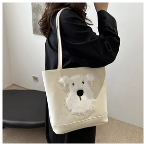 Detail of creamy white tote bag featuring 3D fluffy terrier dog patch and slim shoulder straps