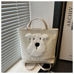Detail of a creamy white tote bag featuring a 3D plush Schnauzer patch and smooth texture