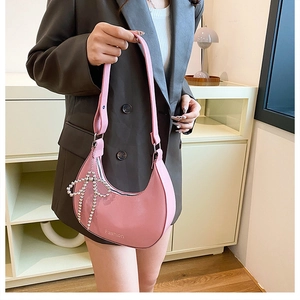 Detailed view of pink patent leather crescent bag with pearl bow and Fashion logo